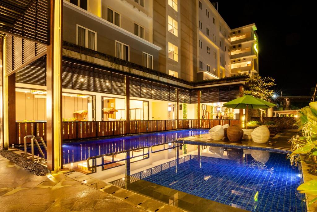 Una piscina frente a un edificio por la noche. en Veronica 1 BR Superior Room ZN24, en Senggigi 
