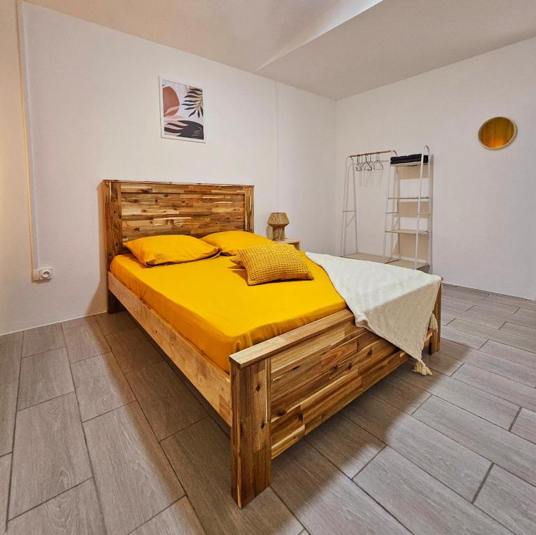 1 dormitorio con cama de madera con sábanas amarillas en La Villa Yéta, détente dans un écrin de verdure, en Petite Île
