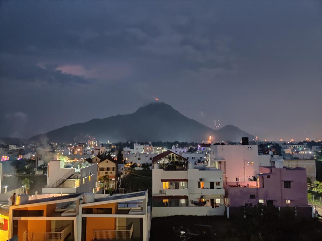 Una ciudad de noche con una montaña en el fondo en Wind Chimes, en Tiruvannāmalai