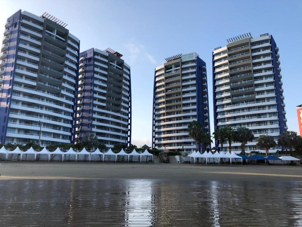 three tall buildings with white umbrellas in front of the water at Tonsupa Diamond Beach in Tonsupa