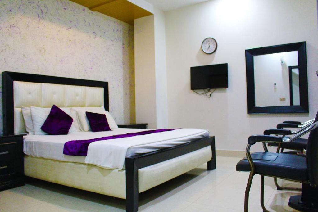 ein Schlafzimmer mit einem Bett, einem Spiegel und einem Stuhl in der Unterkunft Hotel Tulip Inn in Lahore
