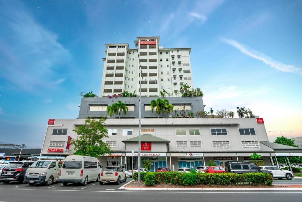 a large white building with cars parked in a parking lot at Inner City Gem - Stunning Views in Cairns