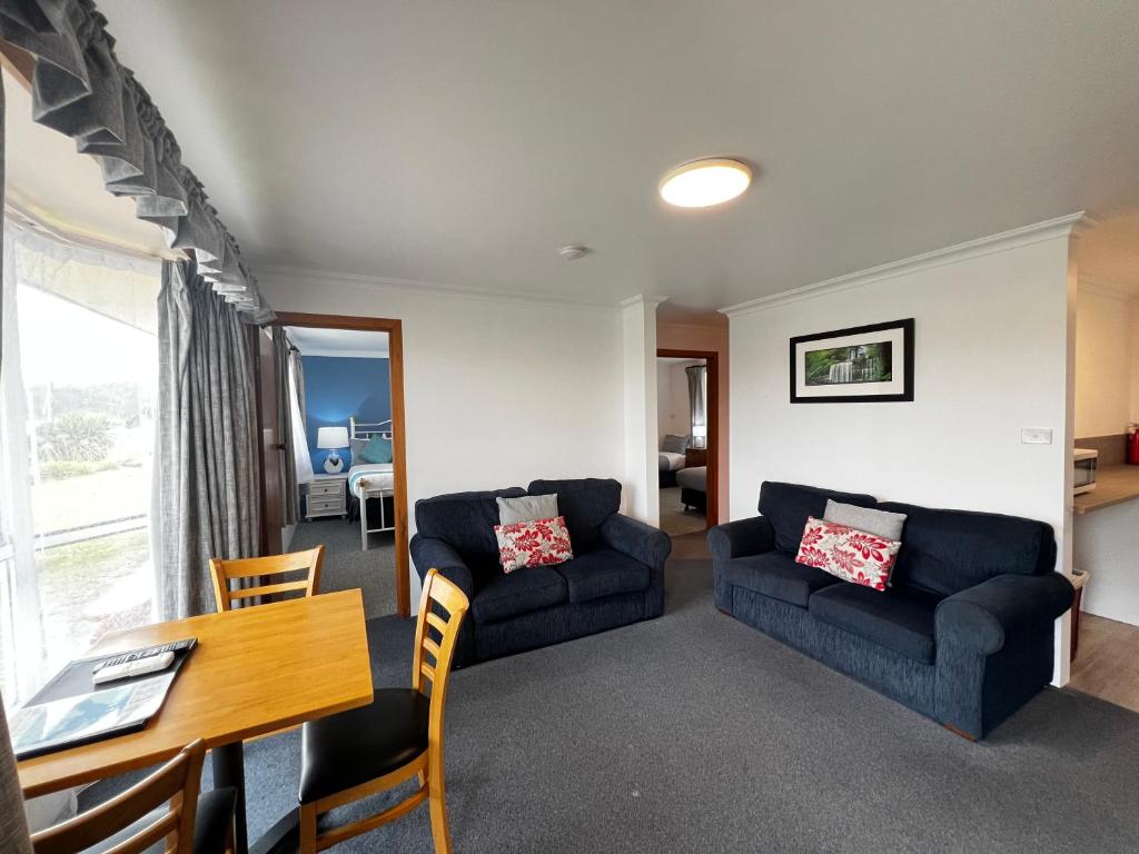 uma sala de estar com dois sofás azuis e uma mesa em Regatta Point Tavern & Holiday Villas em Strahan