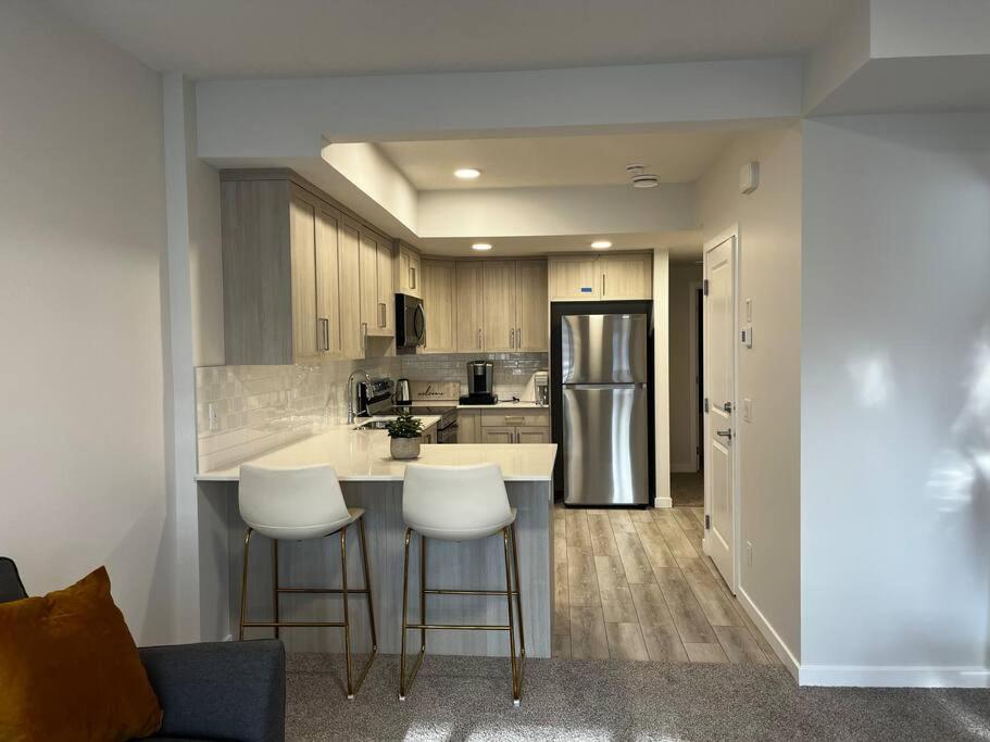 a kitchen with white stools and a refrigerator at Brand New - Home Away from Home in NW Calgary in Calgary