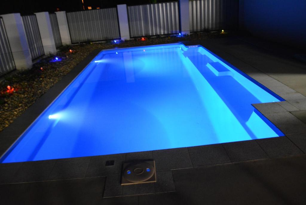 a swimming pool with blue lighting in a backyard at night at Carmila Sands Motel in Carmila