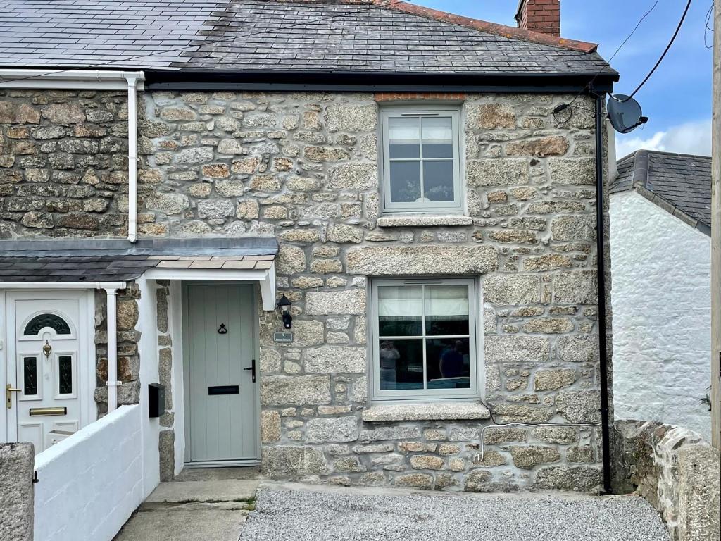 a stone house with a white door and a window at 3 Peters Terrace in Truro