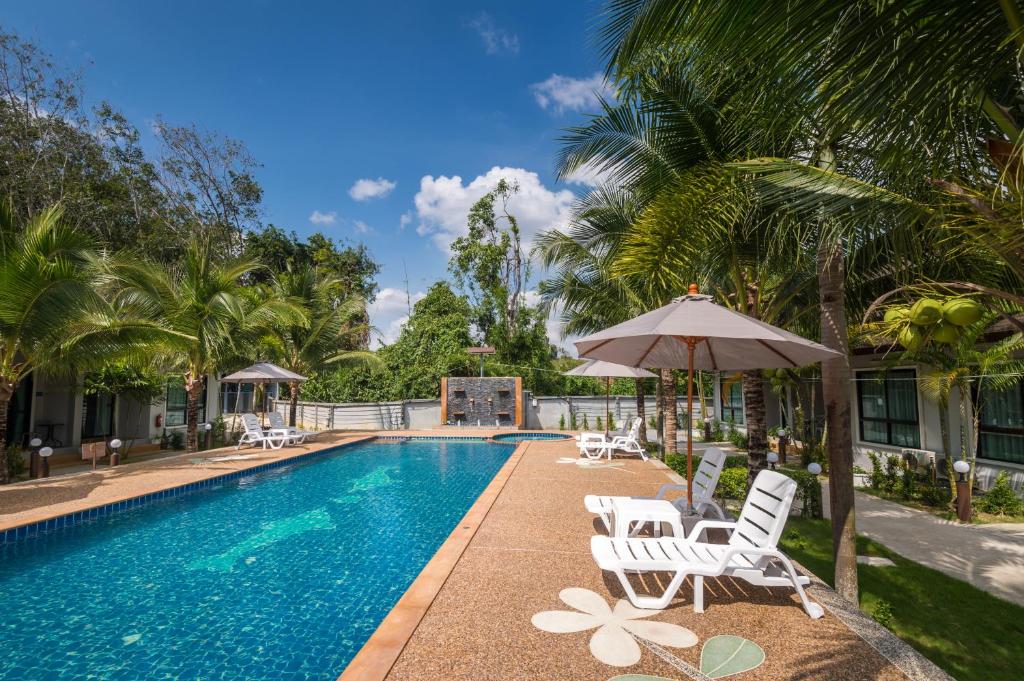 una piscina con sillas, sombrilla y palmeras en Mook Anda Villa, en Ao Nang Beach