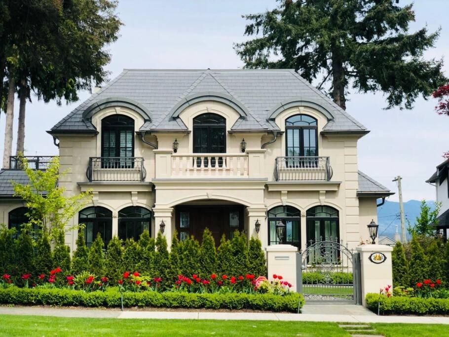 a white house with red flowers in front of it at Luxury 5-bedrooms in Vancouver Point Grey in Vancouver