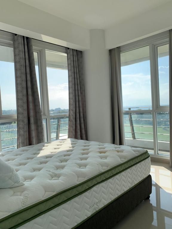 un letto in una camera con una grande finestra di Two Bedroom Apartment at The Nove Nuvasa Bay Nongsa 306 a Nongsa