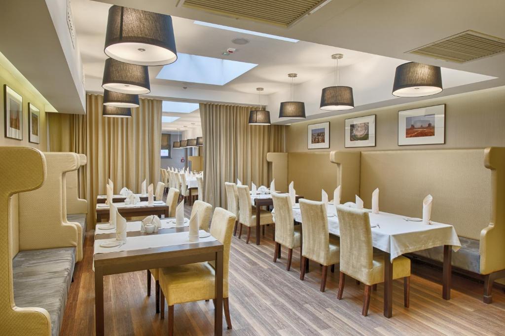 restauracja z białymi stołami i żółtymi krzesłami w obiekcie Hotel Lazur SPA & Conference w Kaliszu