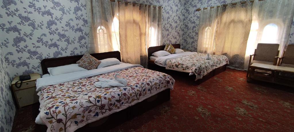 a bedroom with two beds and two windows at Hotel Bakhtawar in Srinagar