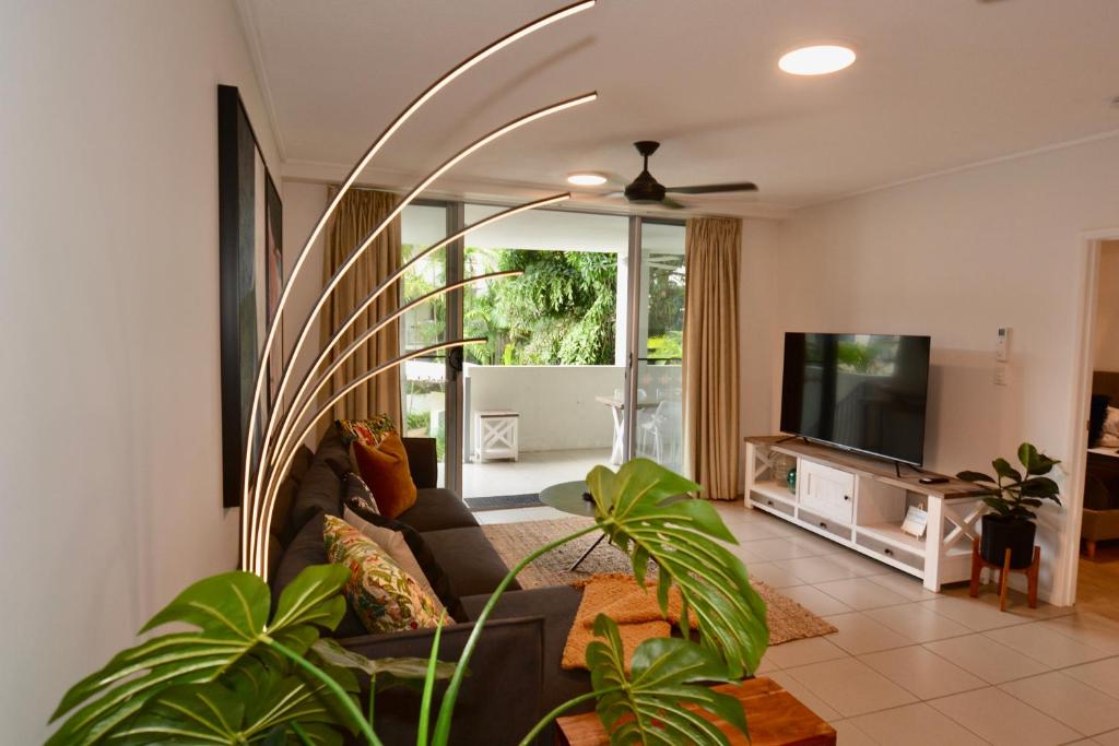 a living room with a couch and a flat screen tv at Tropical Luxe Apartment in Townsville