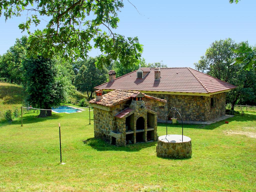 a stone house with a gambrel roof on a yard at La Buenaventura del Tiétar in Casavieja