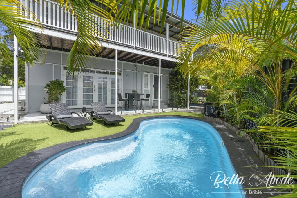 a pool in the backyard of a house with palm trees at Bella Abode on Bribie - Loft with Pool in Bongaree