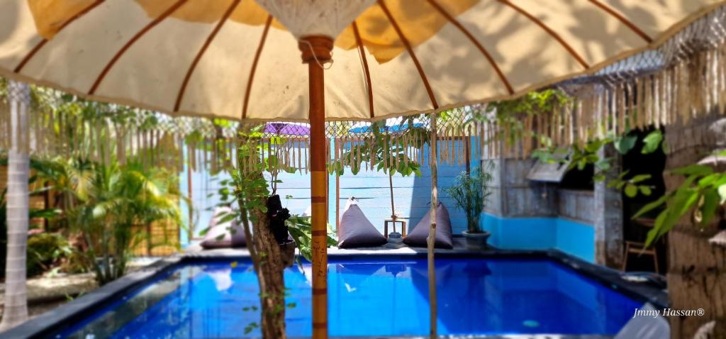 a swimming pool with an umbrella next to it at Villas Light House - Eco-Traditional Joglo in Gili Trawangan