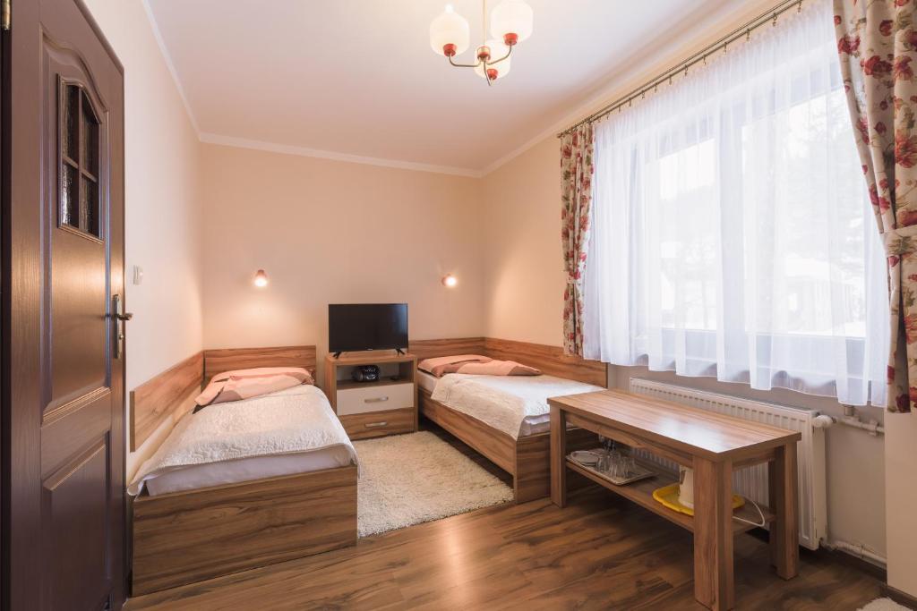 een slaapkamer met 2 bedden, een tafel en een raam bij Pokój u Zosi in Zakopane