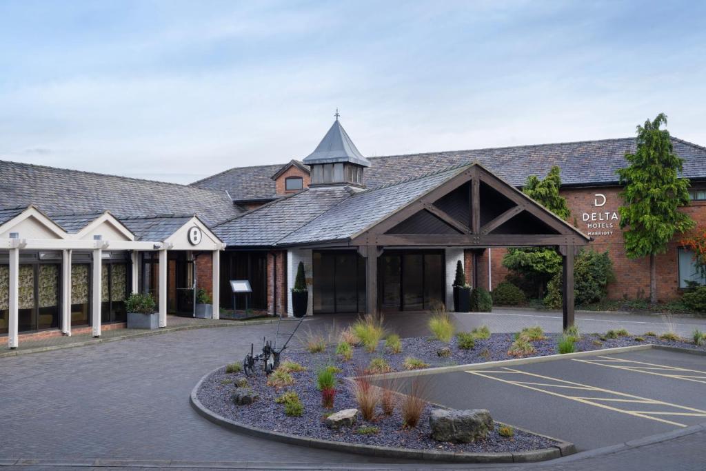 a building with a parking lot in front of it at Delta Hotels by Marriott Manchester Airport in Hale