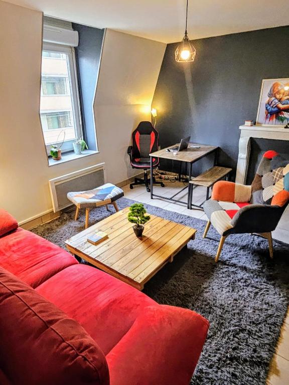 a living room with a red couch and a table at Chambre d&#39;Hôtes calme et cosy, à 3min de la gare, centre ville, avec un lit de 160cm in Nevers