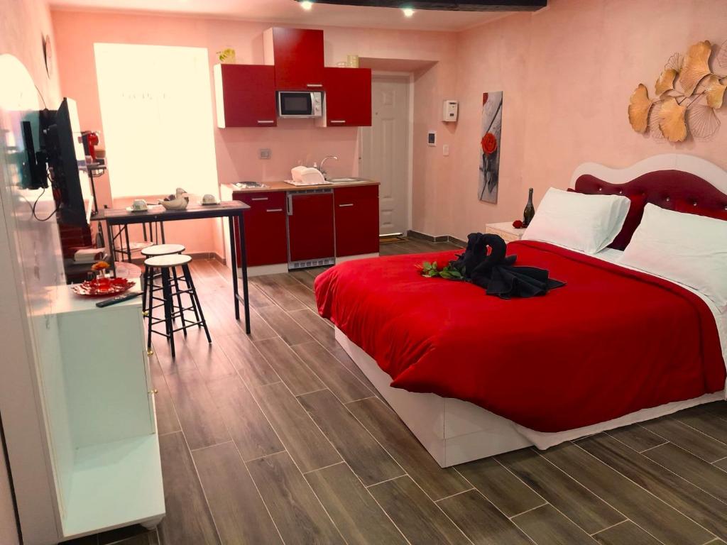 a bedroom with a red bed and a kitchen at IL NIDO Suite in Fiuggi