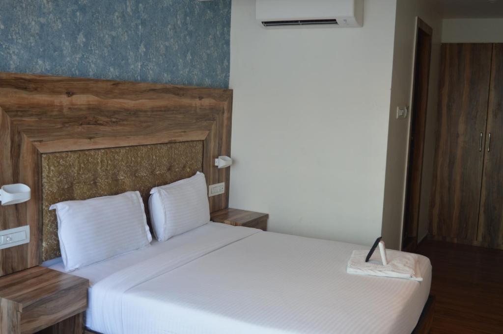 um quarto com uma cama branca e uma cabeceira em madeira em Hotel Godrej Avenue VFS Global em Mumbai