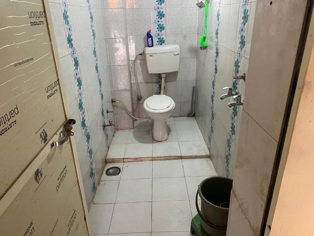 een kleine badkamer met een toilet en een tegelvloer bij Sahu Home stay in Ujjain