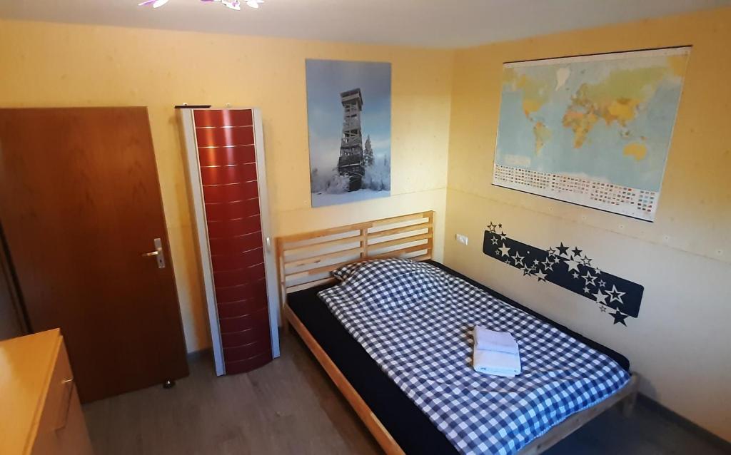 a small bedroom with a bed with a blue and white checkered blanket at Kellerwaldturm Apart-Room in Jesberg