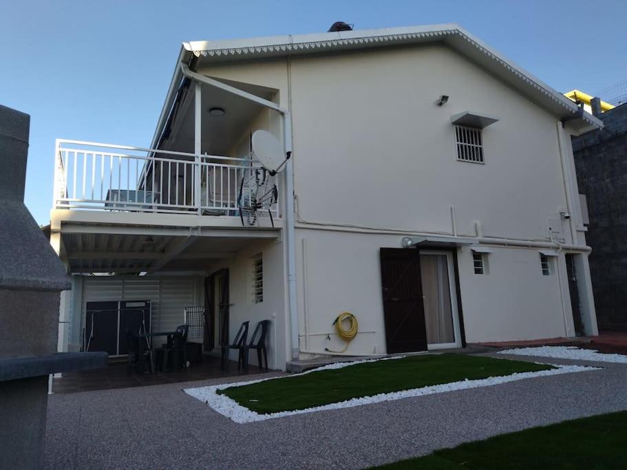 a white building with a balcony and a patio at La Villa Les Bambous . in Sainte-Marie