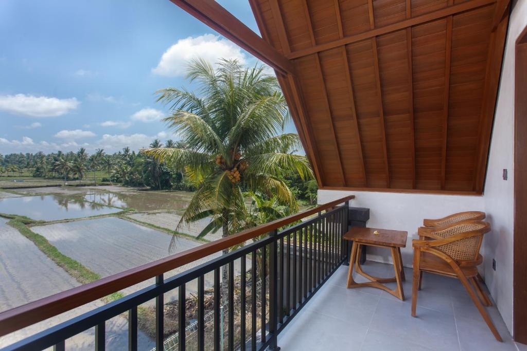 einen Balkon mit Blick auf eine Palme in der Unterkunft Ikada Villa by Pramana Villas in Ubud