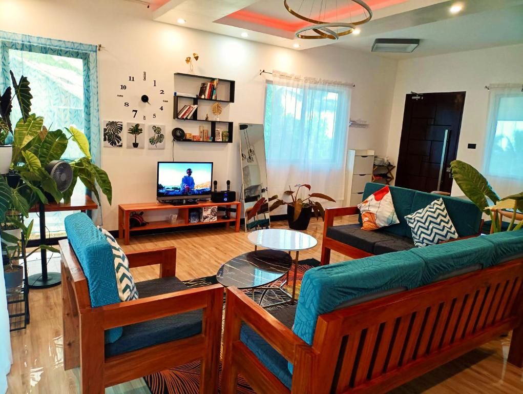 uma sala de estar com um sofá e uma televisão em Bushis Crib Staycation Farmhouse em Panubigan