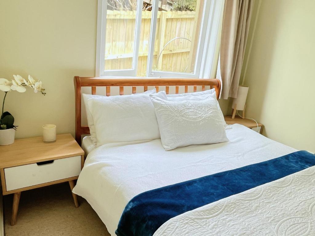 a bedroom with a white bed with a window at Family suite at Campbells Bay -Netflix TV in Auckland