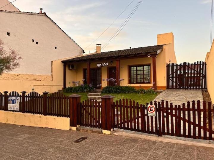 ein Zaun vor einem Haus mit einem Gebäude in der Unterkunft Casa para 7 personas pileta in Monte Hermoso