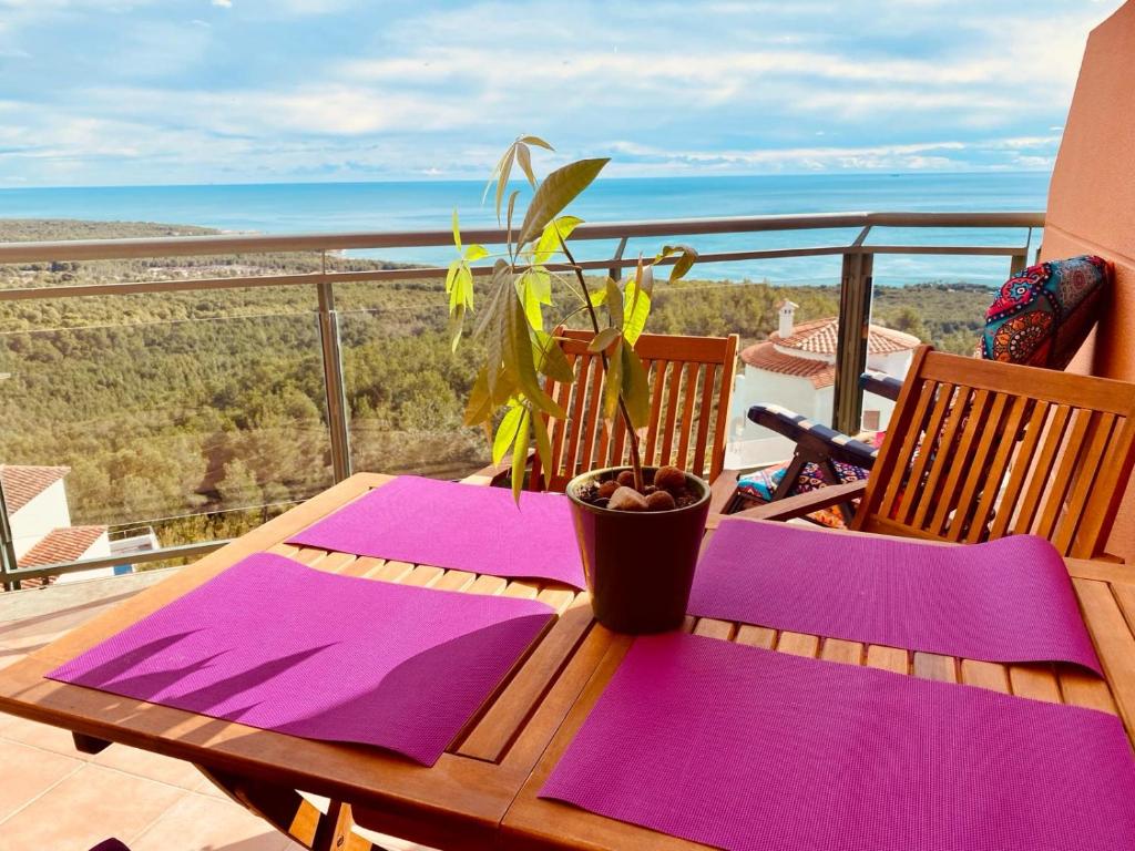 ein Holztisch mit lila Servietten und einer Pflanze auf einem Balkon in der Unterkunft Precioso ático en la Sierra de Irta in Alcossebre