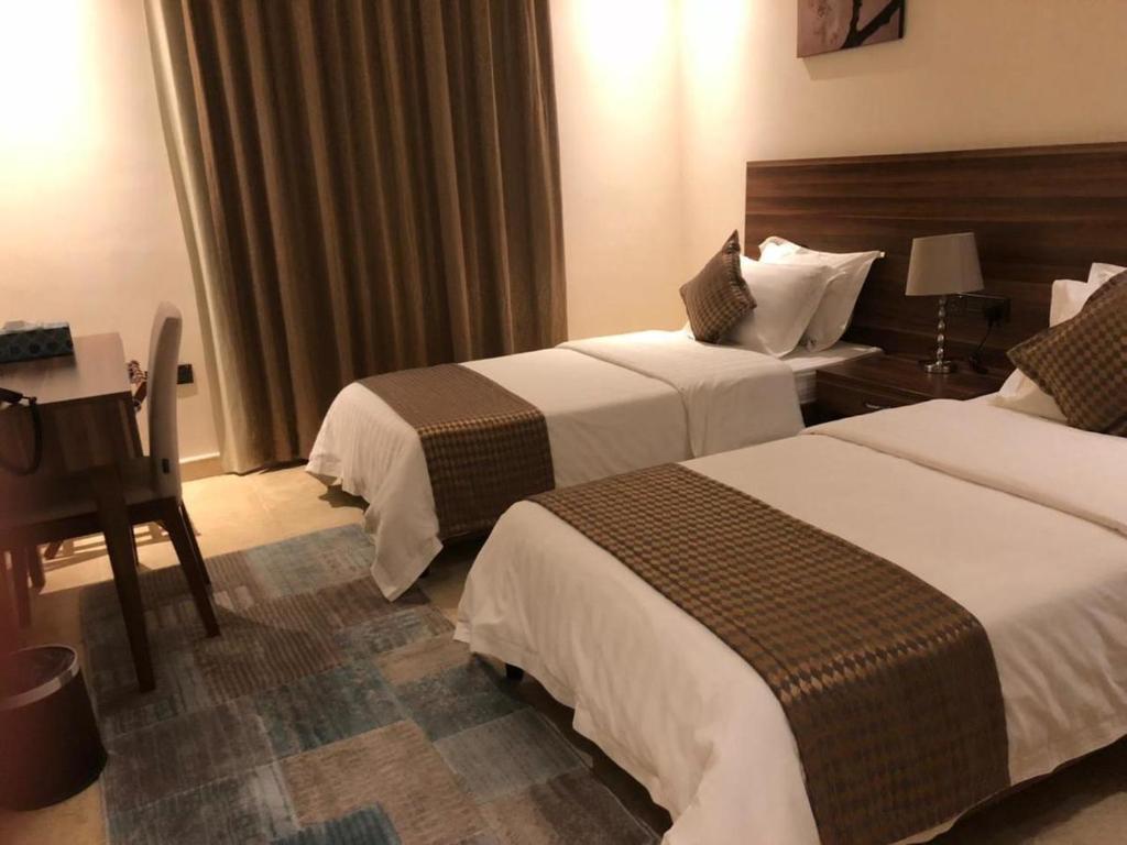 a hotel room with two beds and a desk at منتجع ريف خزيمة - الياسمين in Al Madinah