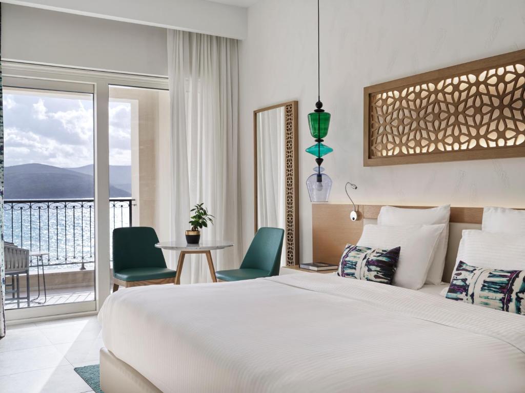 a hotel room with a bed and a balcony at The Chedi Luštica Bay in Tivat