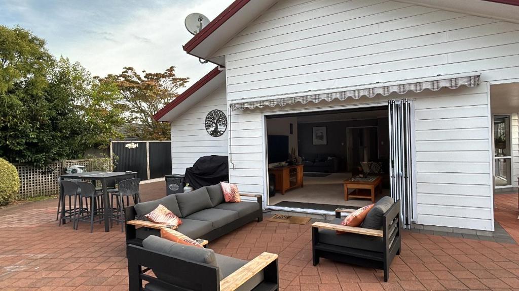 a patio with a couch and chairs in front of a house at River Heights in Taupo