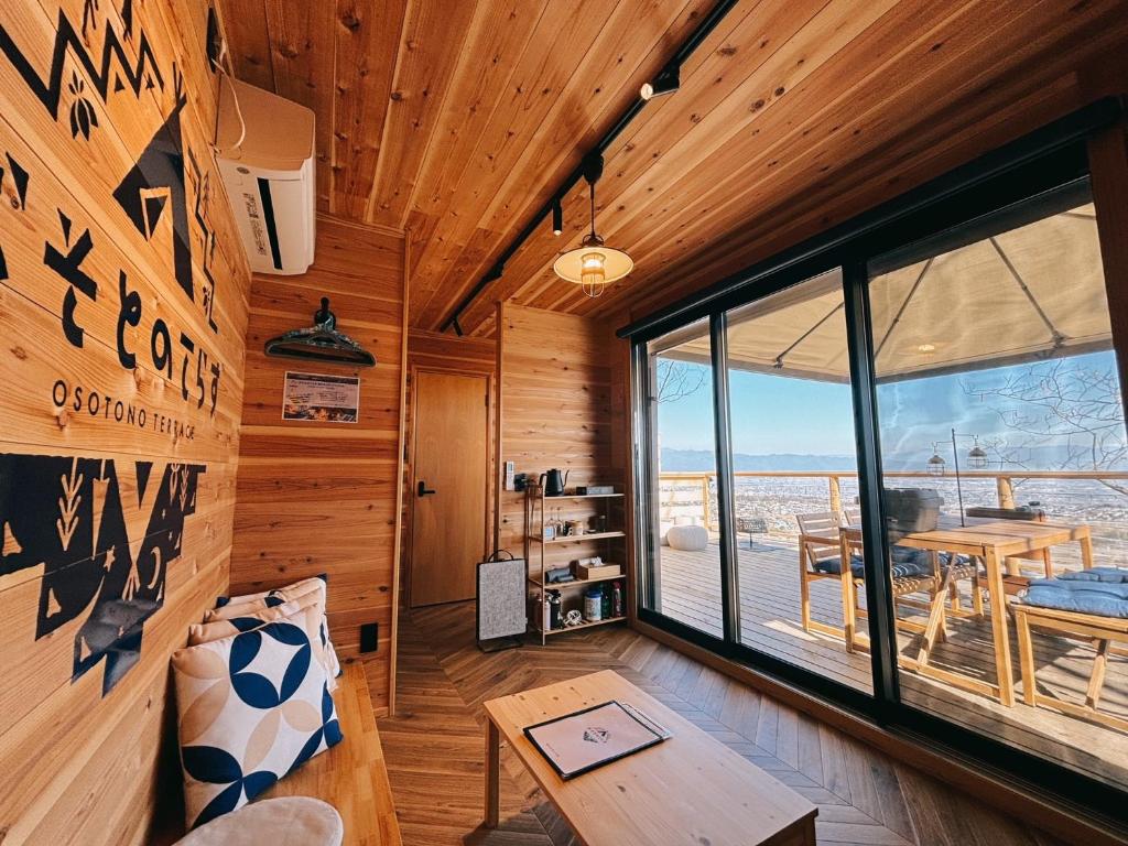 Pokój z drewnianymi ścianami i dużym oknem w obiekcie おそとのてらす　南アルプス w mieście Minami Alps