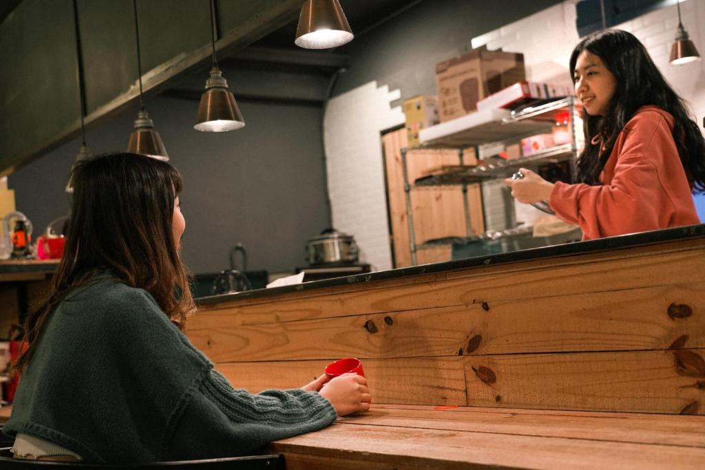 a woman sitting at a counter talking to a girl at Meeting Mates Hostel in Taipei