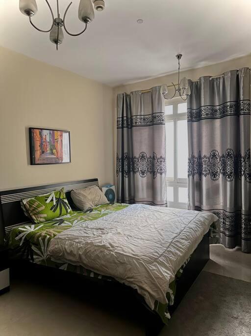 een slaapkamer met een bed met gordijnen en een kroonluchter bij Luxury room in al nahda 2 in Dubai