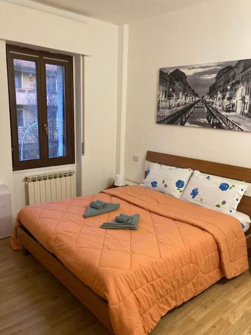 1 dormitorio con 1 cama grande con manta naranja en Rhospitality - Pasubio 34, en Cornaredo