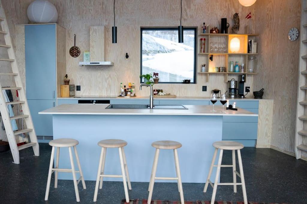 uma cozinha com um lavatório e dois bancos de bar em Cozy Retreat and danish design in Nature's Splendor, Sogn, Norway, Jacuzzi-option available em Sogndal