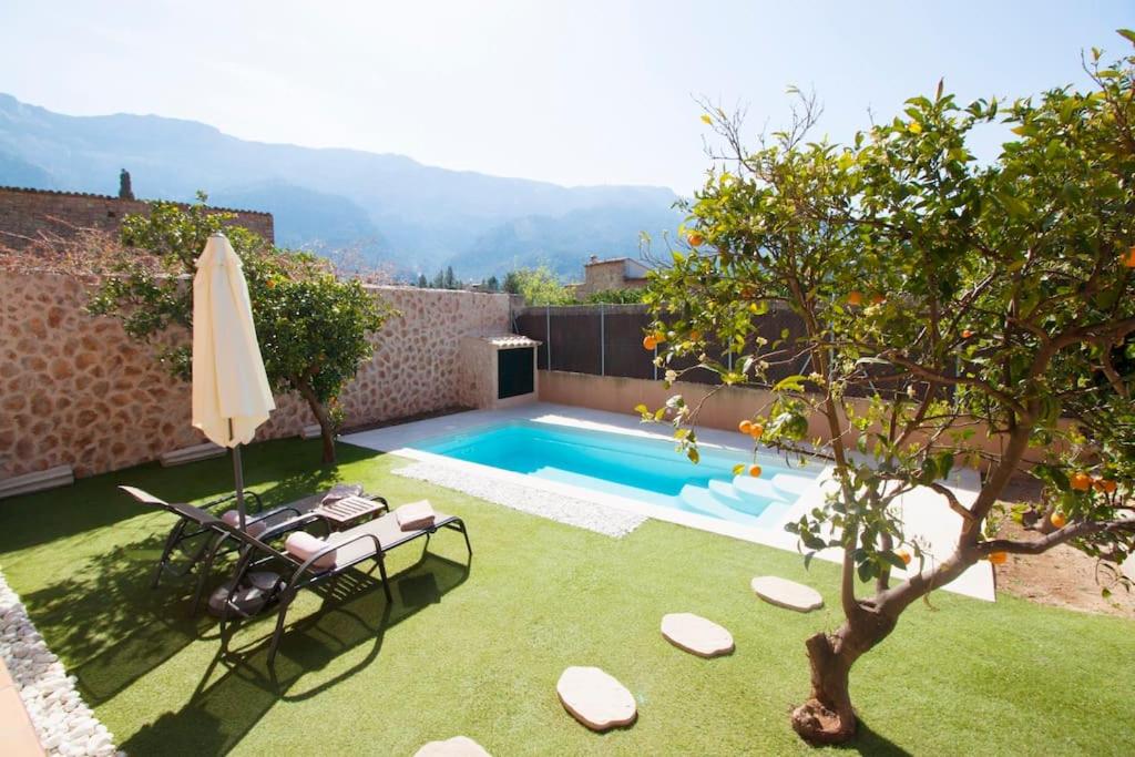 a backyard with a swimming pool and an umbrella at Ground floor with garden, swimming pool and private parking in Sóller