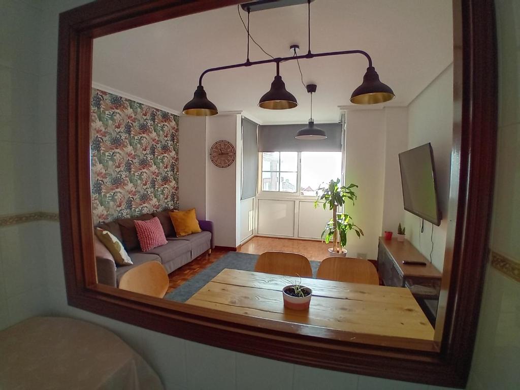 a mirror reflecting a living room with a table and a couch at Dúplex Saja in San Vicente de la Barquera