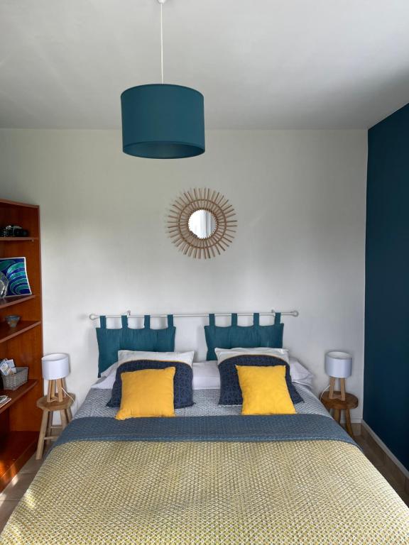 a bedroom with a bed with blue and yellow pillows at maison aux volets bleus in Quévert
