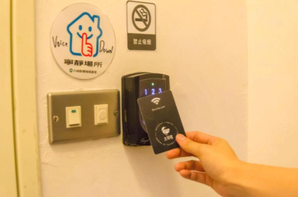 a person holding a remote control in front of a wall at Meeting Mates Hostel in Taipei