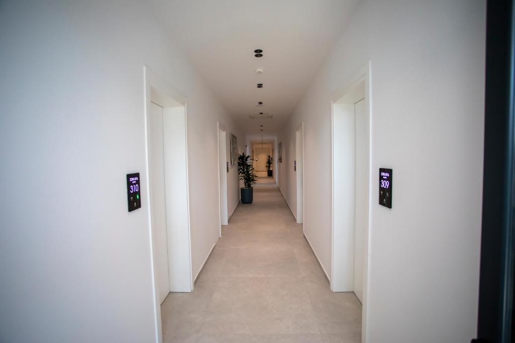 a hallway with white walls and a long hallway with a plant at Resort Zdrava in Savër