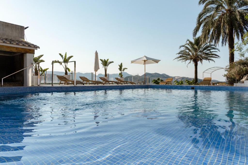 a large swimming pool with chairs and palm trees at Finca de L’ANGLÉS Casa Poniente in Potríes