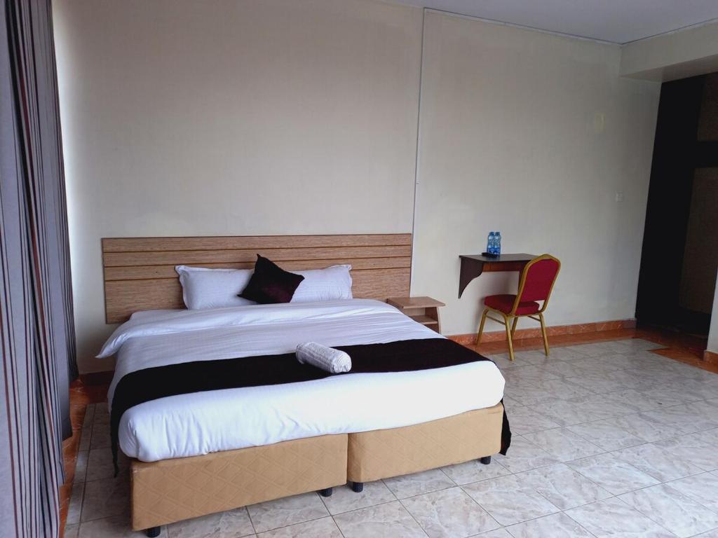 a bedroom with a large bed and a chair at Fahari Bliss Hotel in Nairobi