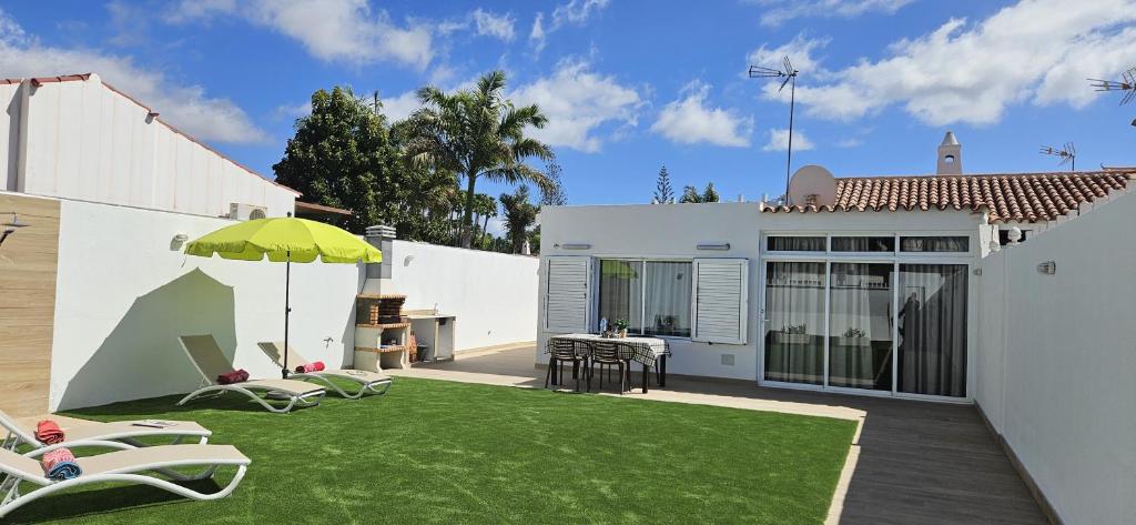 a backyard with a lawn with chairs and an umbrella at Villa Solycan 15 in Playa del Ingles
