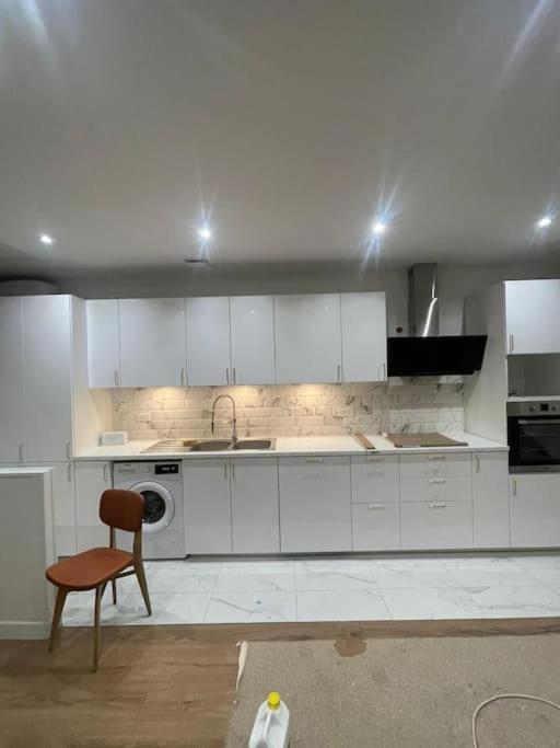 - une cuisine avec des placards blancs, une chaise et un évier dans l'établissement Maison plein pied à Livry G., à Livry-Gargan