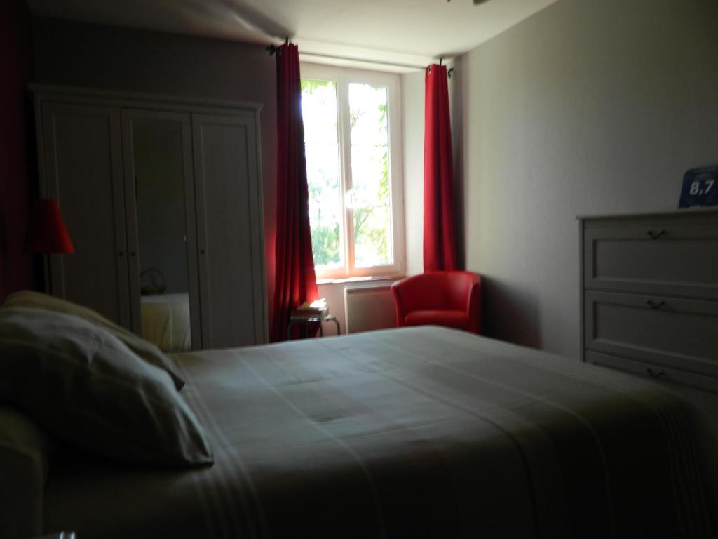 - une chambre avec un lit et une fenêtre avec des rideaux rouges dans l'établissement Meublés de tourisme La Reserve, à Saint-Pierre-les-Bois